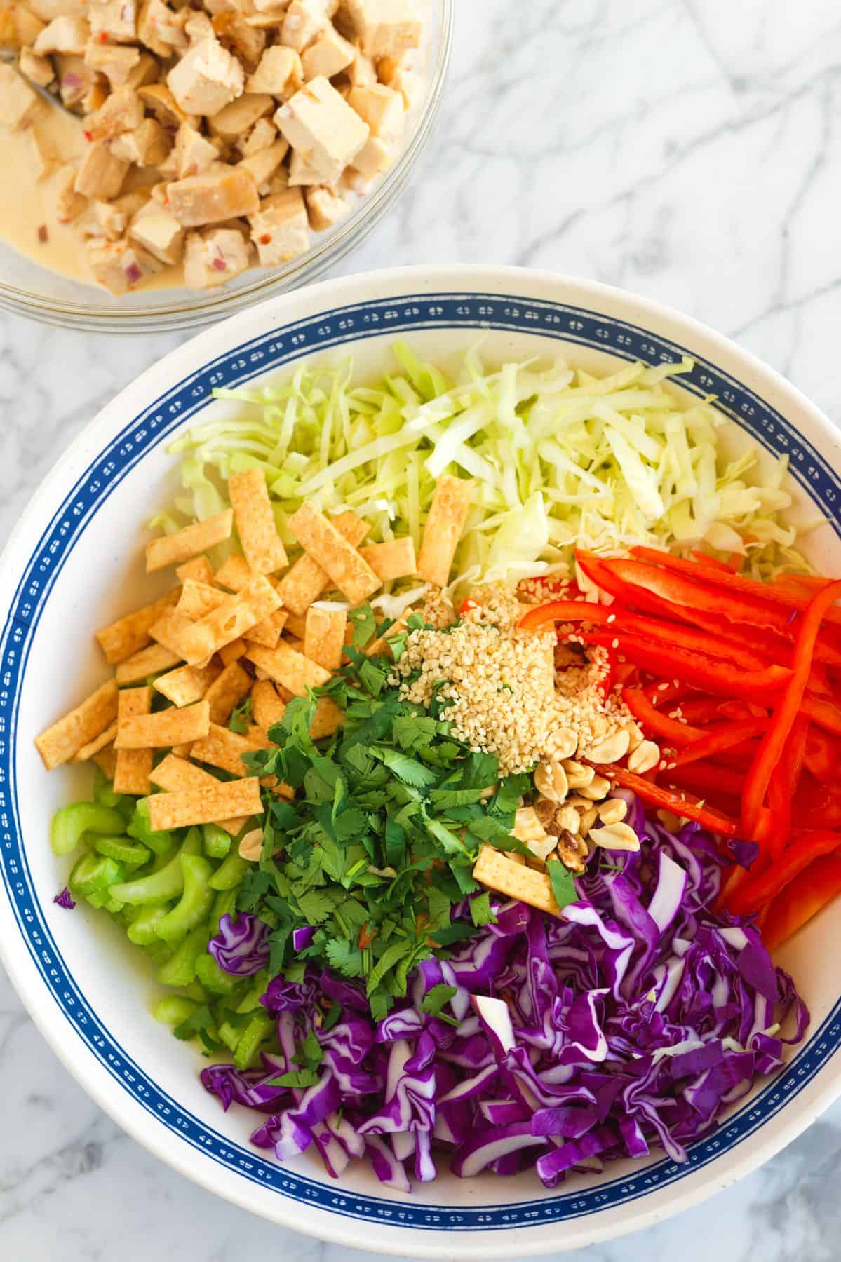 All of the ingredients in a bowl to make Thai chicken salad