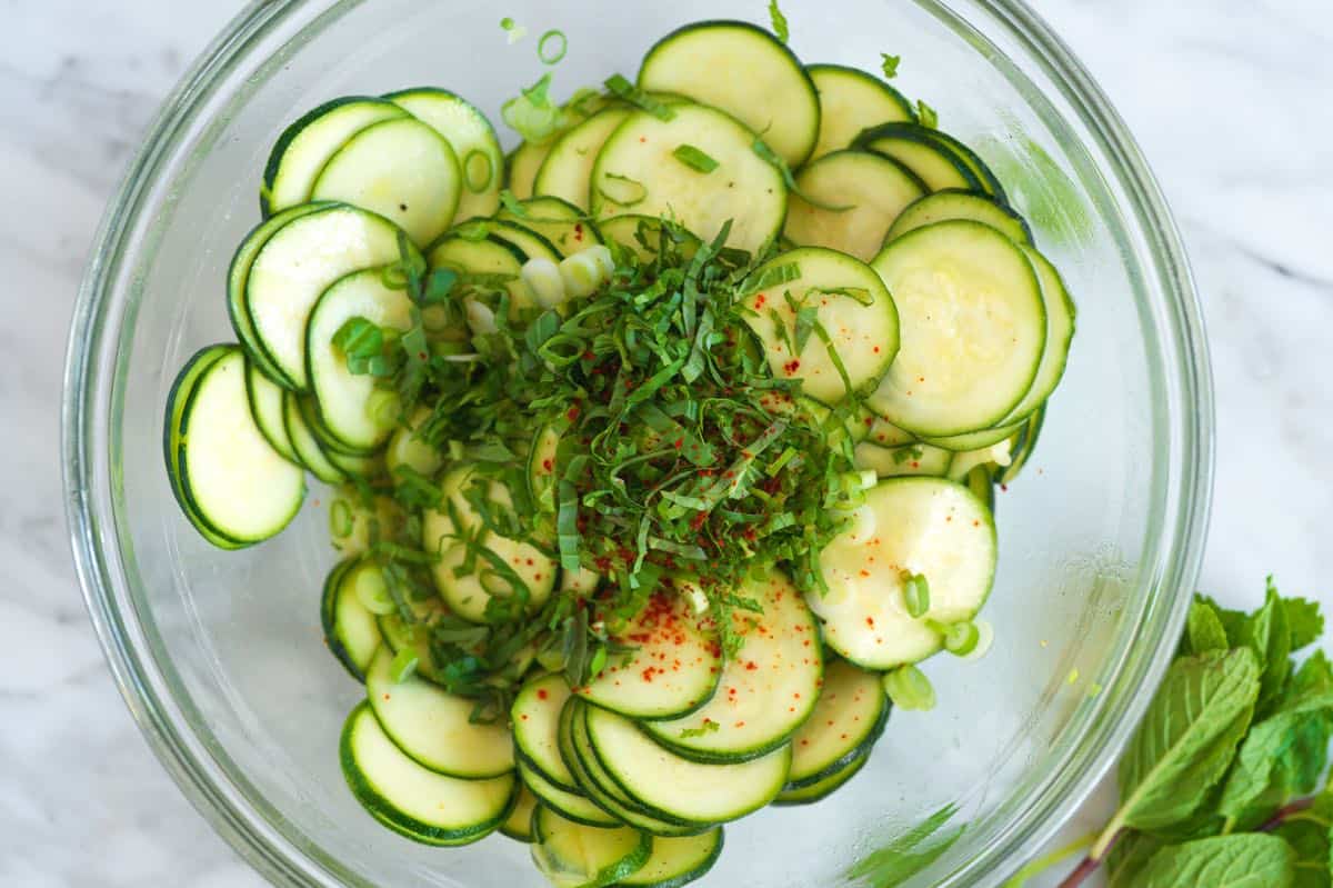 Tossing the marinated zucchini with herbs