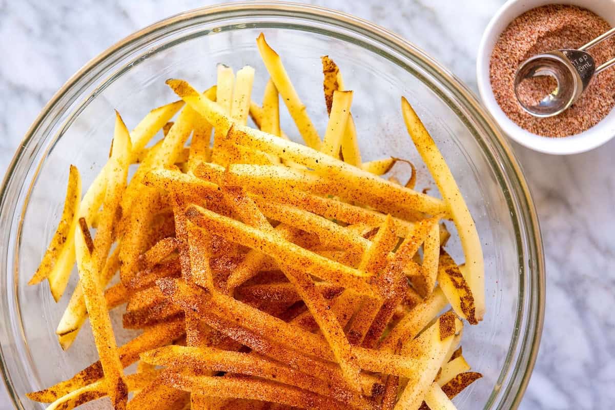 How to Make French Fries: tossing cut and soaked potatoes with seasoned salt before baking