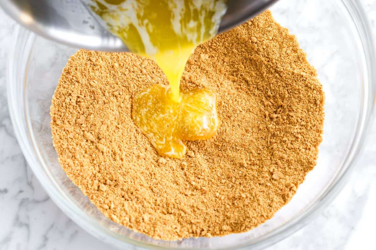 How to Make Graham Cracker Crust - Adding butter to the graham cracker crumbs.
