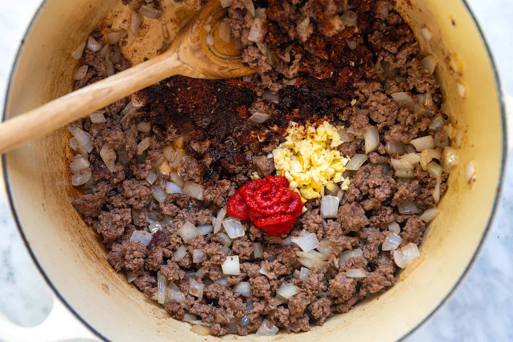 Building flavor for homemade chili with garlic and tomato paste.