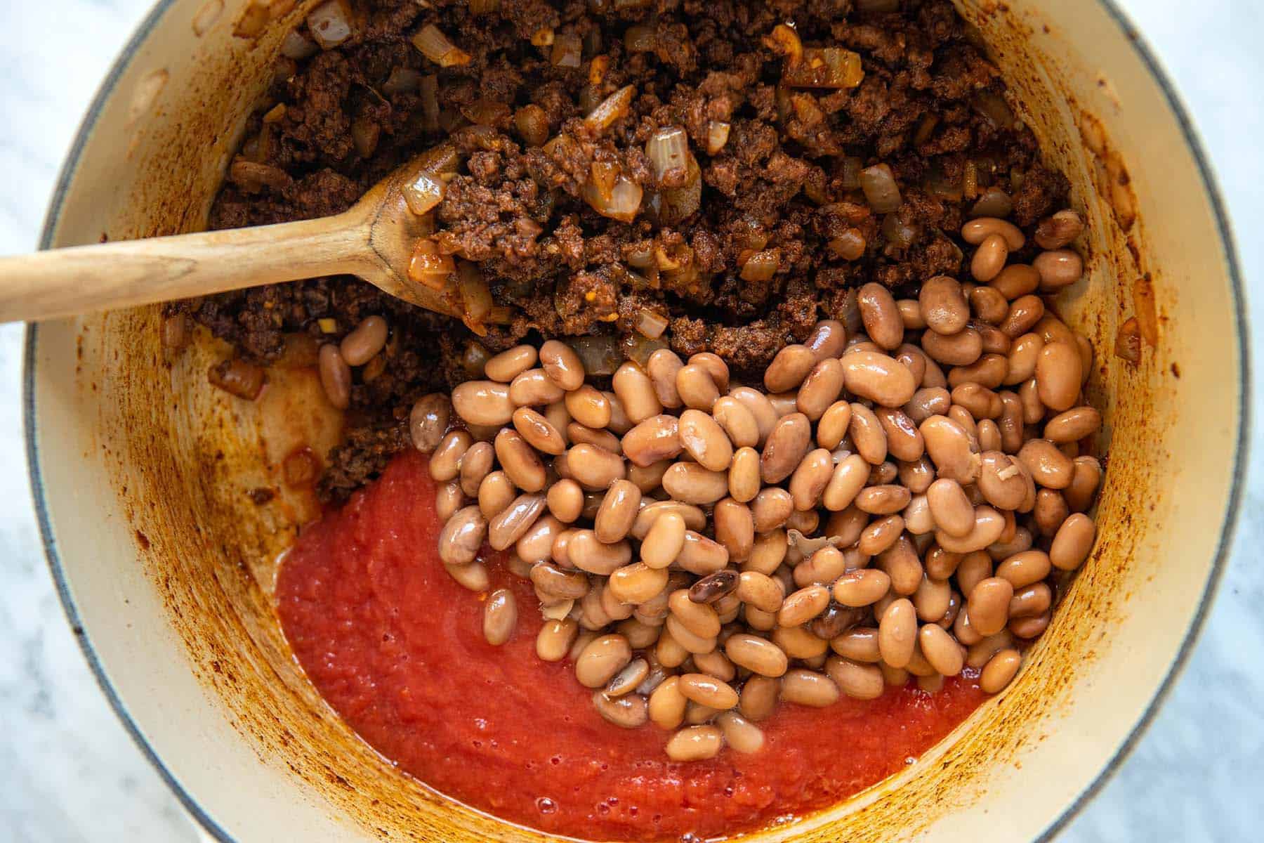 Adding beans to a pot of chili.