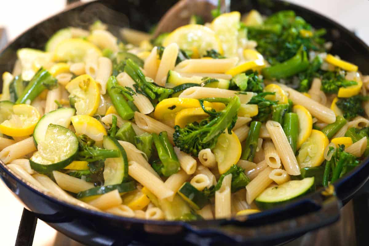 Tossing vegetables and pasta with the pasta primavera sauce