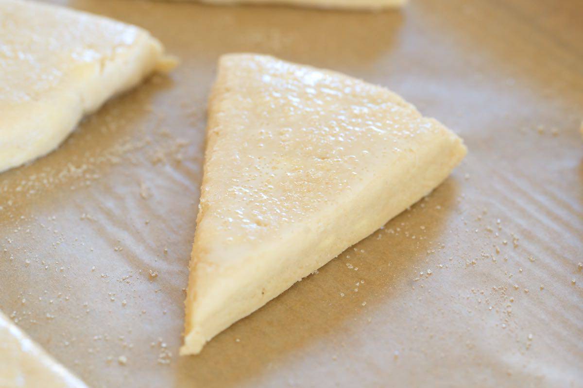 Scones ready to bake with cream and sugar added to the top