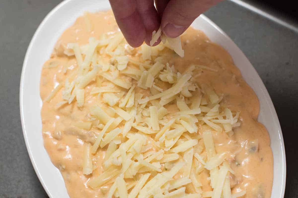 Adding cheese to the top of buffalo chicken dip
