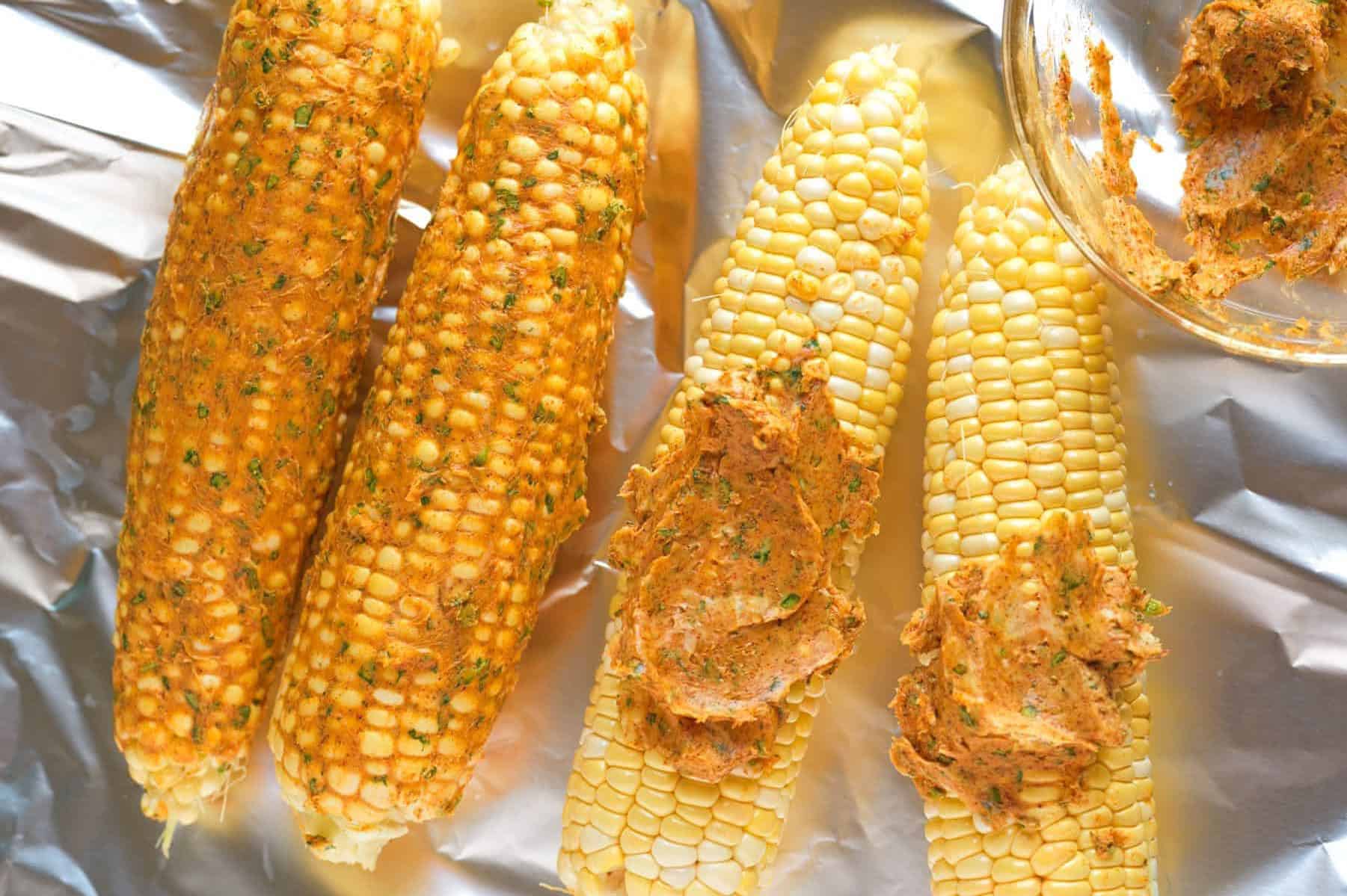 Spreading Cajun butter over ears of corn