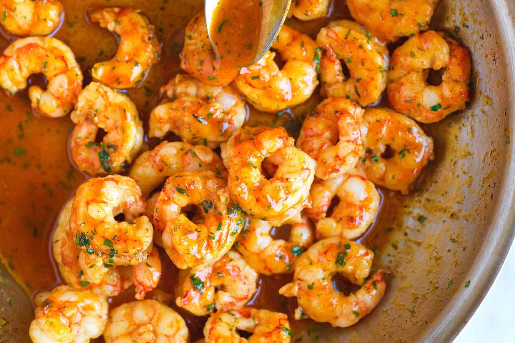 Swirling Cajun butter into a skillet with barely cooked shrimp