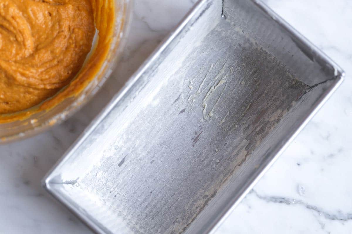 Flouring pan to make pumpkin bread