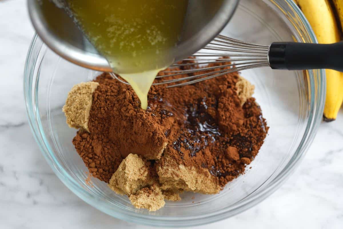 Mixing cocoa and sugars with warm melted butter for chocolate banana bread batter
