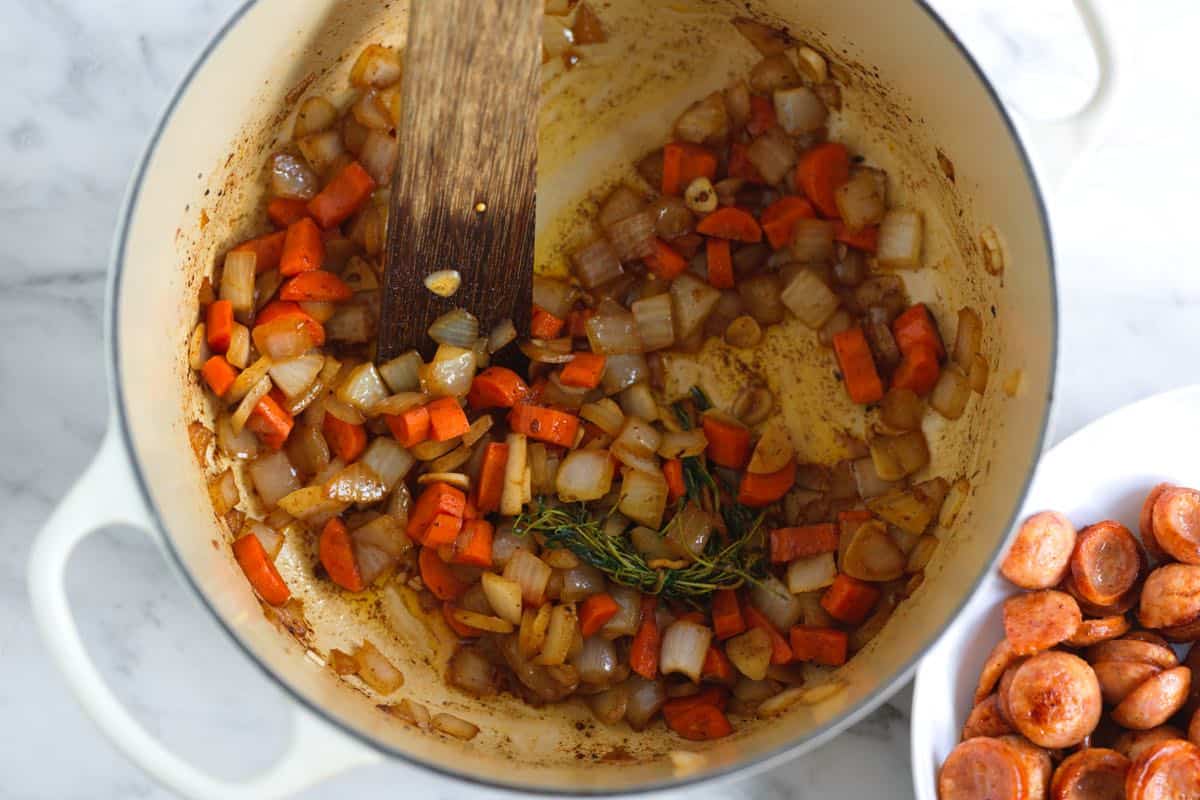 Making sauerkraut soup with rendered bacon and kielbasa fat, carrots, and onions.
