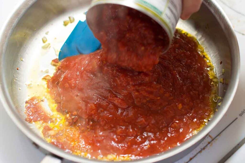 Adding tomato sauce to skillet
