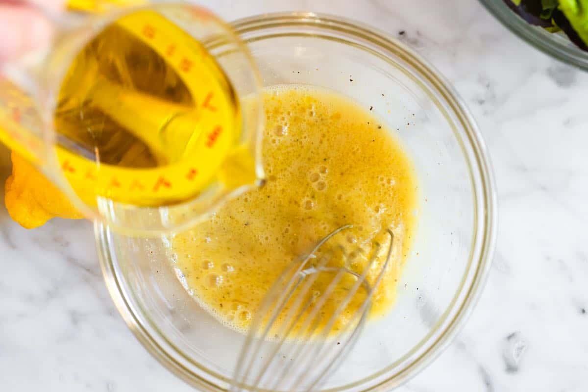 Whisking olive oil into lemon juice to make lemon vinaigrette