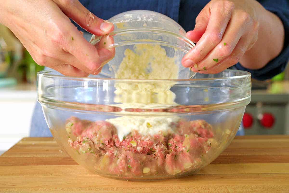 Adding the panade (milk and saltine crackers) to the meatball ingredients