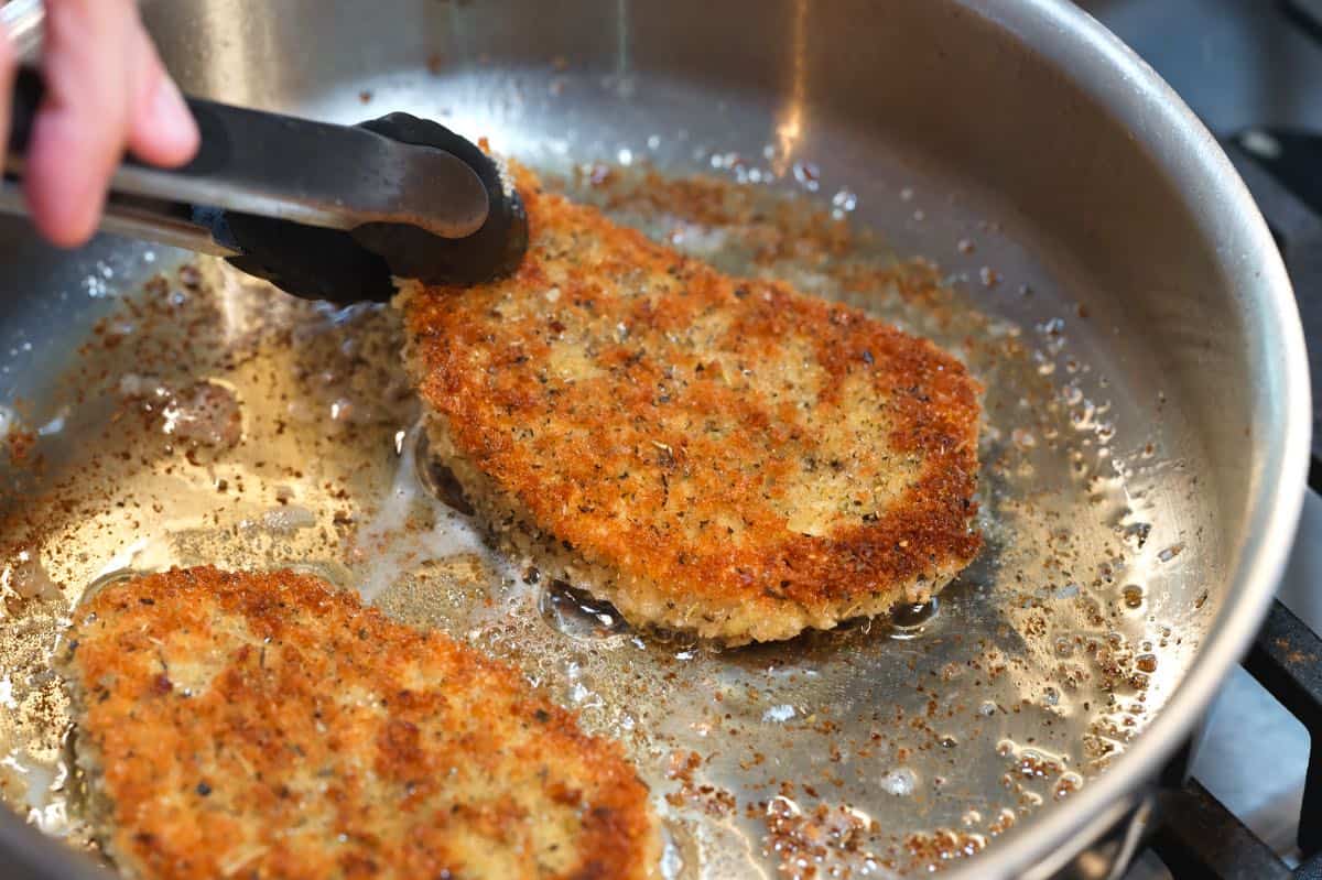 Pan-frying pork chops breaded in breadcrumbs for pork milanese