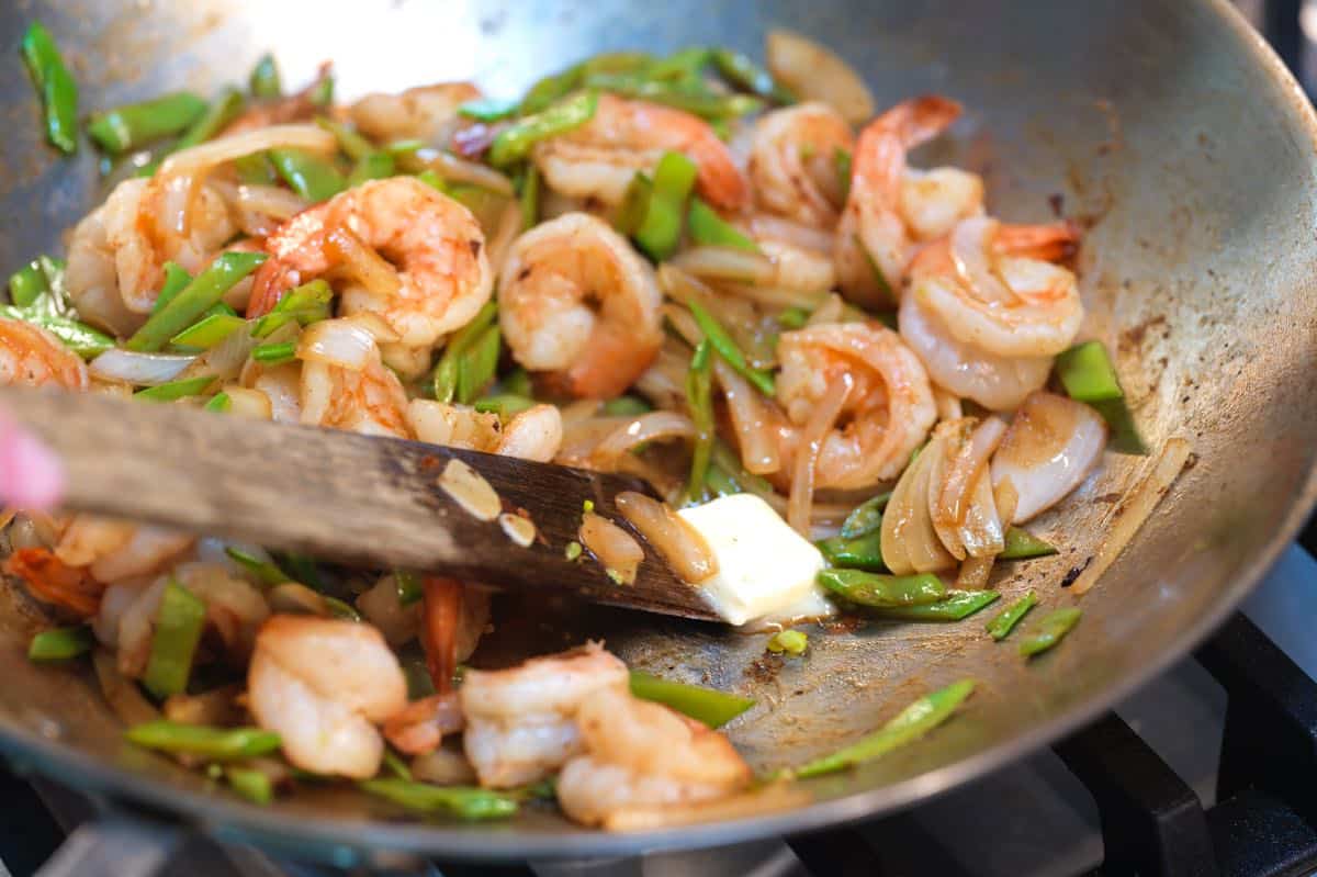 Finishing the shrimp stir fry with a bit of butter to make the sauce creamy.