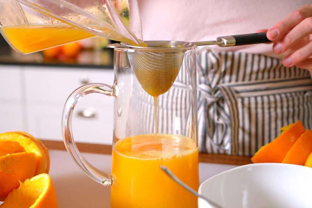 Straining fresh orange juice to remove pulp