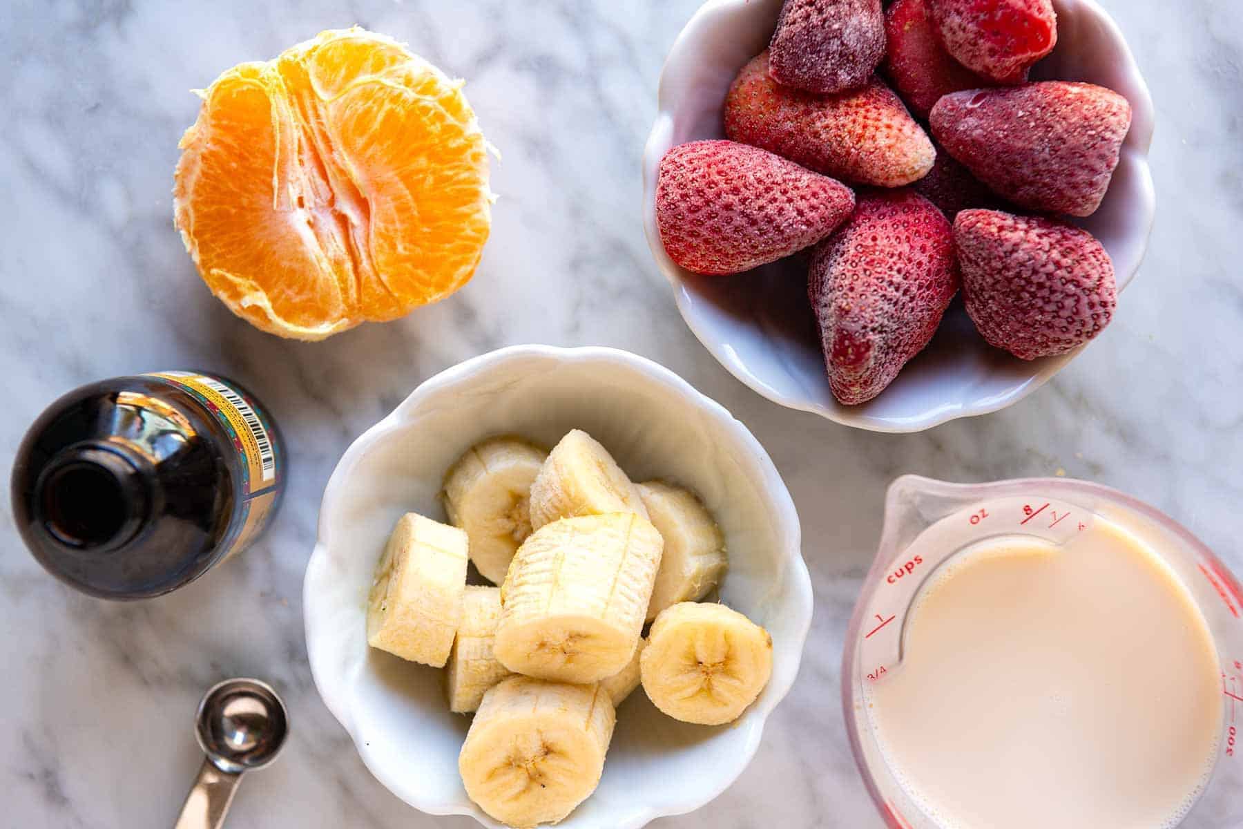 Ingredients for a Strawberry Smoothie (bananas, strawberries, orange, and milk)