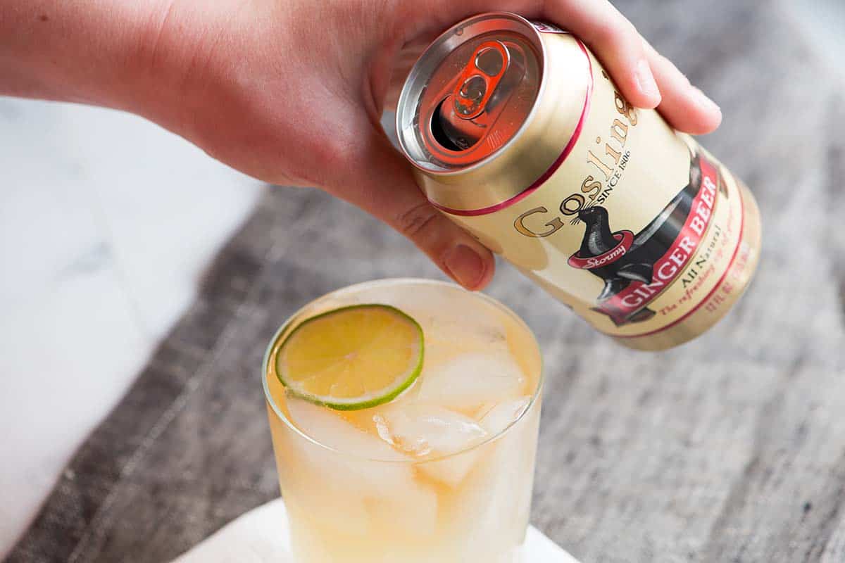 Adding ginger beer to dark rum and ice