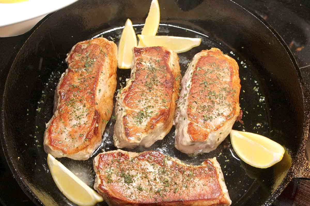Seared pork chops in a skillet ready to go into the oven.