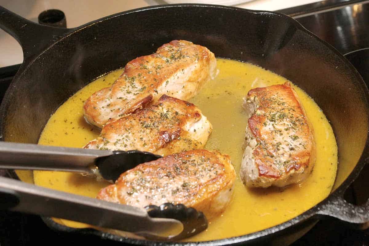 Placing baked pork chops into the quick pan sauce