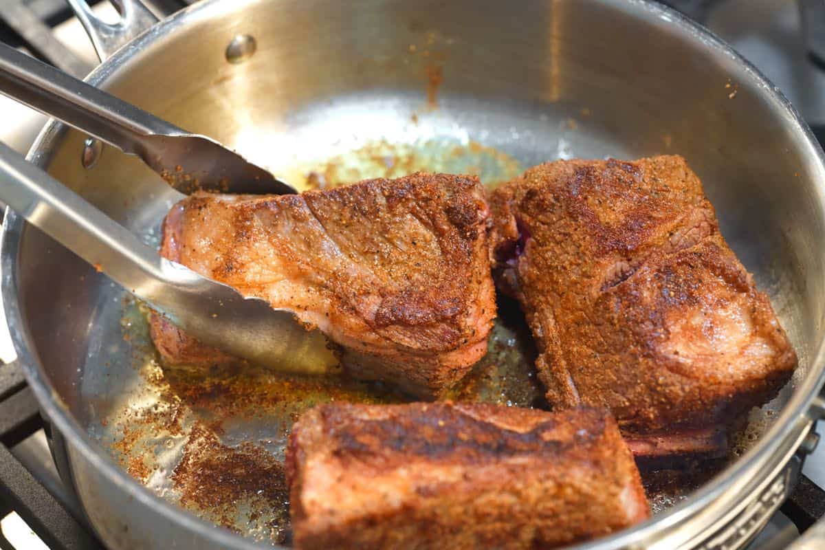 Searing short ribs rubbed with BBQ dry rub