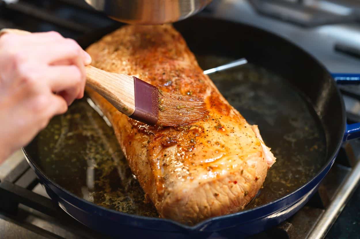 Brushing the glaze all over the seared pork loin before roasting in the oven