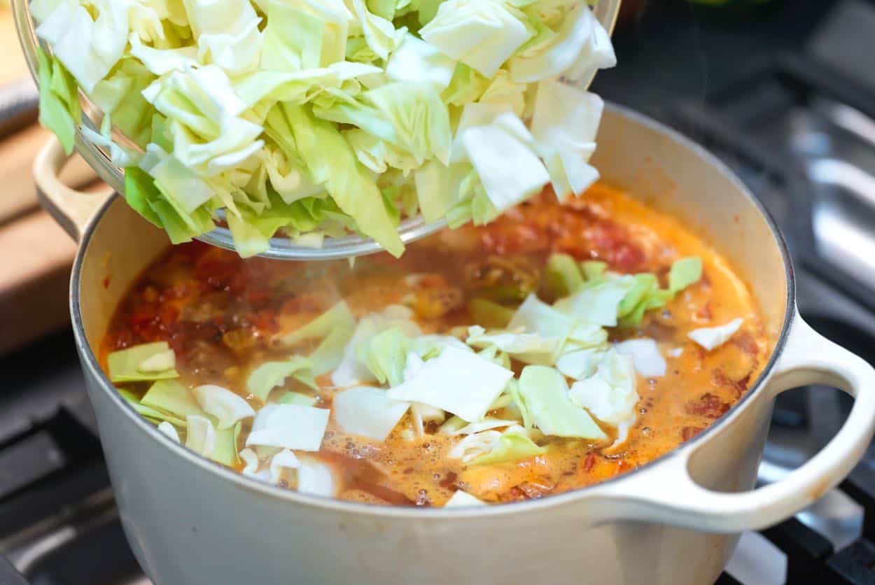 Adding lots of cabbage to a soup pot for cabbage soup