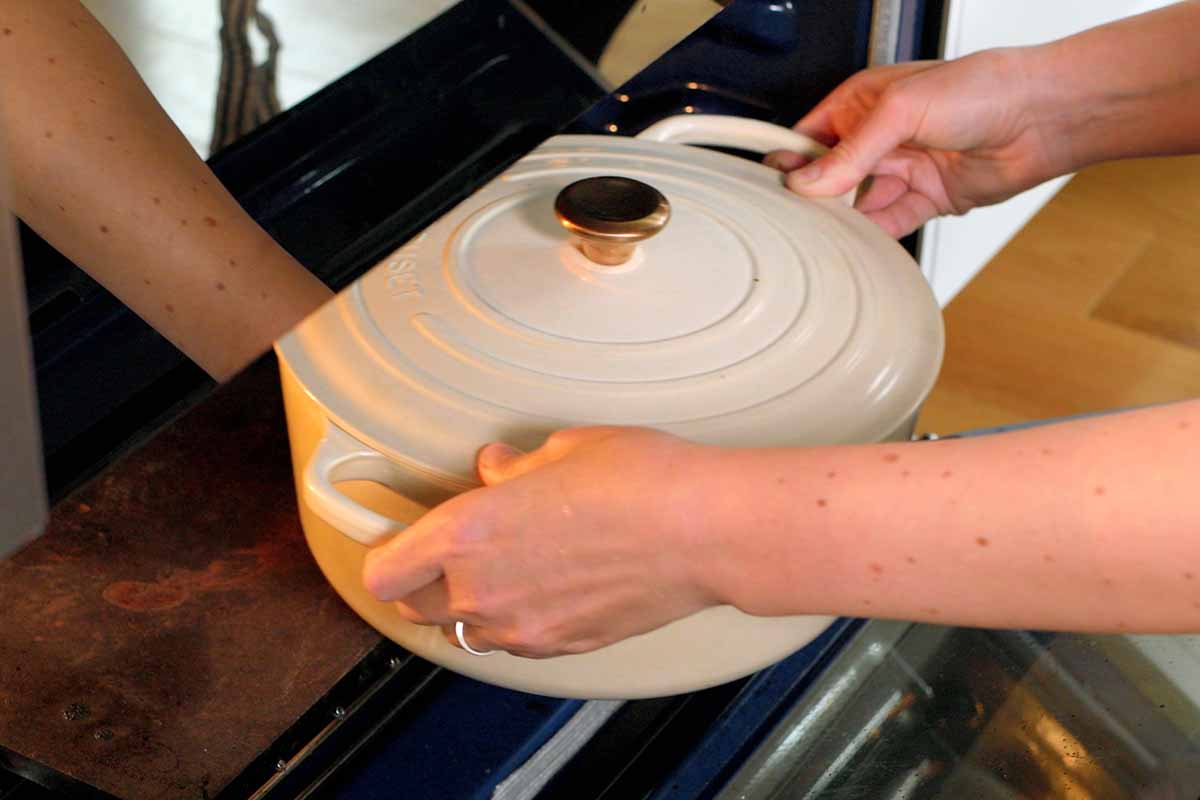 Placing a Dutch oven in the oven to make carnitas