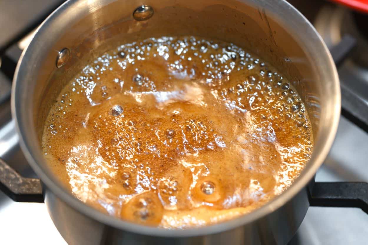 Simmering ham glaze with brown sugar and honey on the stove