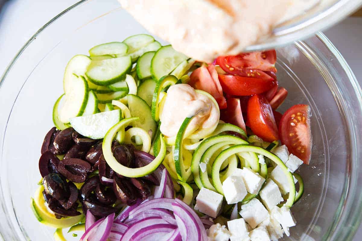 Adding Greek yogurt dressing to zucchini noodle salad