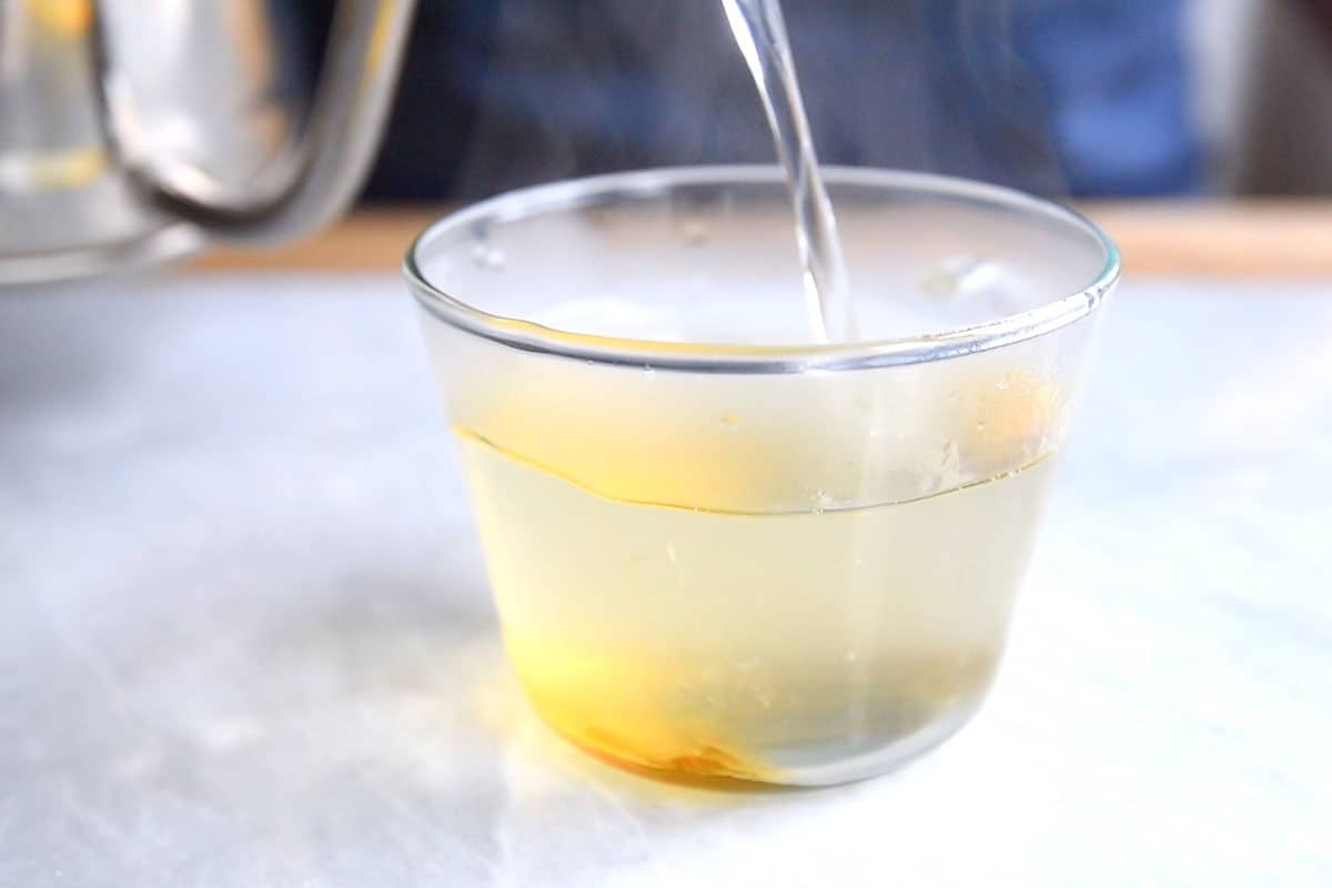 Pouring hot water into a mug with honey for a hot toddy