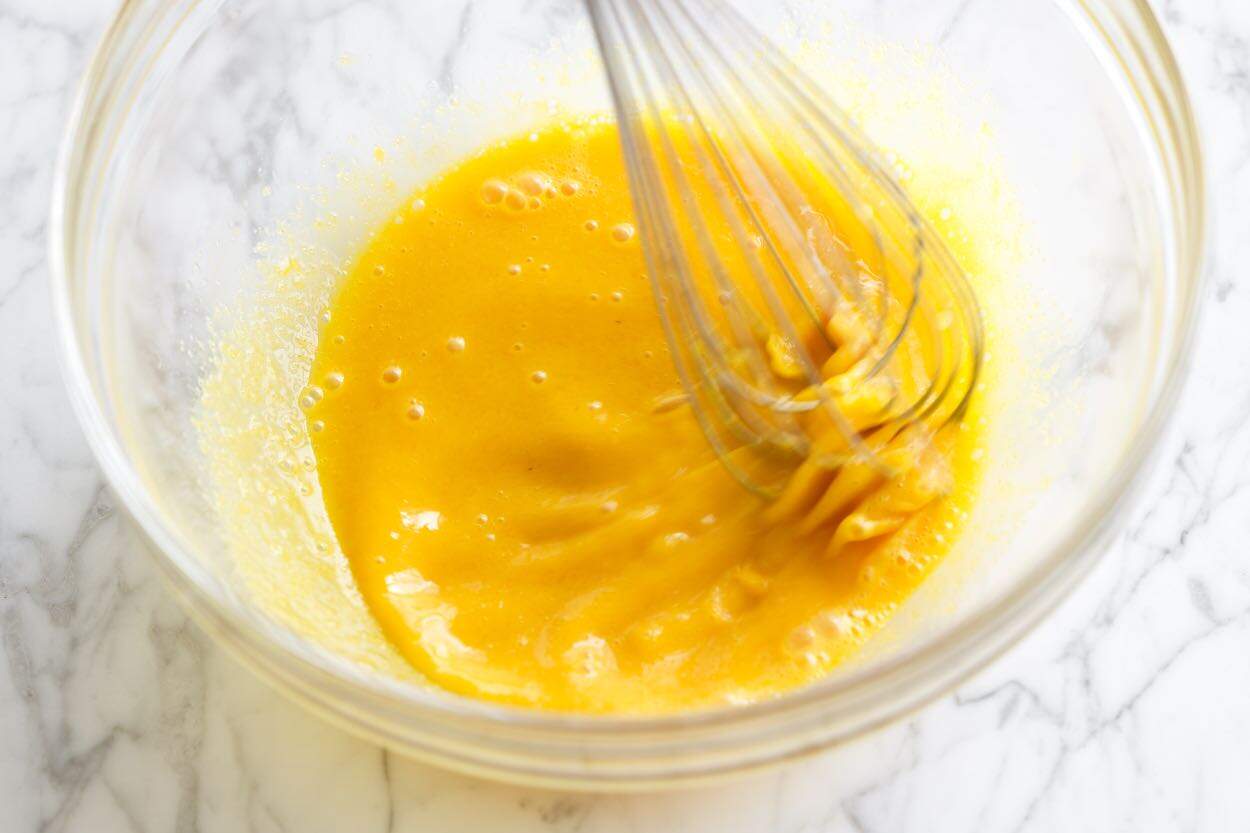 Whisking egg yolks, sugar, and Marsala wine before cooking them over a double boiler.