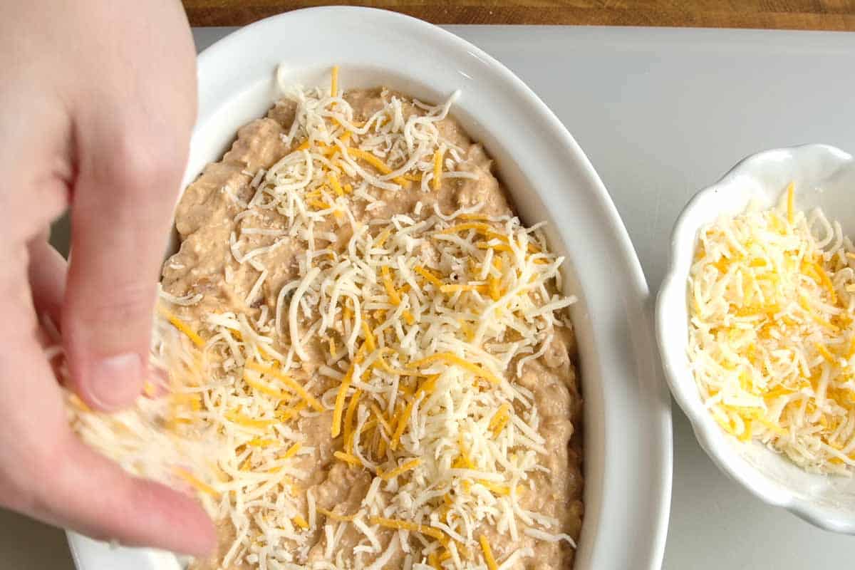 Adding two layers of cheese to the bean dip before baking in the oven