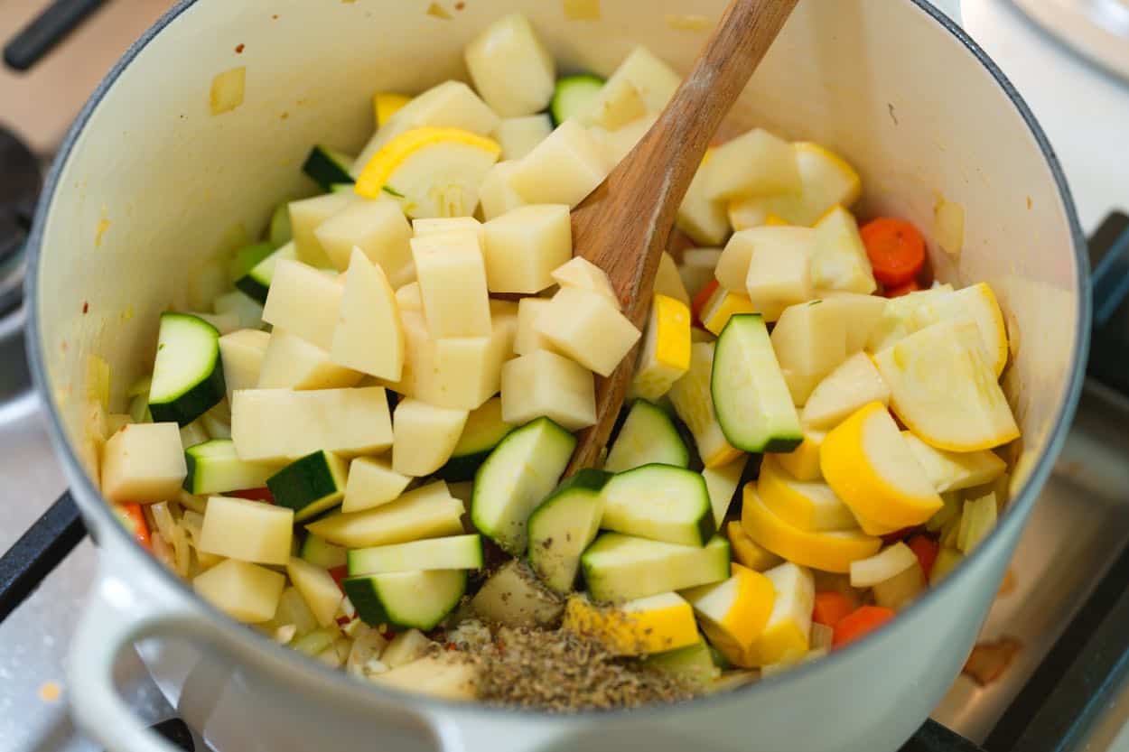 Adding the garlic, Italian seasoning, potatoes, and zucchini to the soup pot