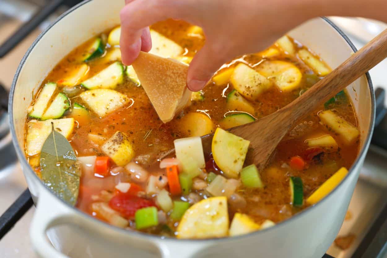 Putting a Parmesan rind into the broth before simmering.