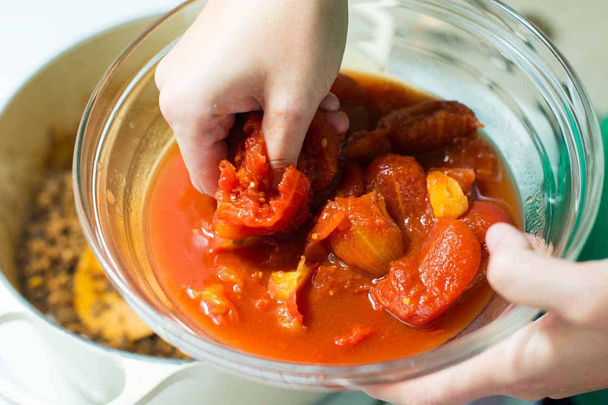 Breaking up whole peeled tomatoes for the chili