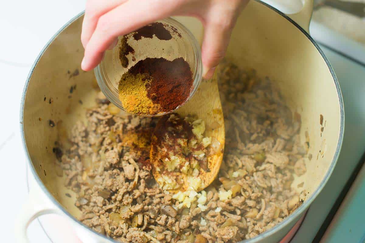 Adding spices to browned ground turkey, onions, and mushrooms for chili