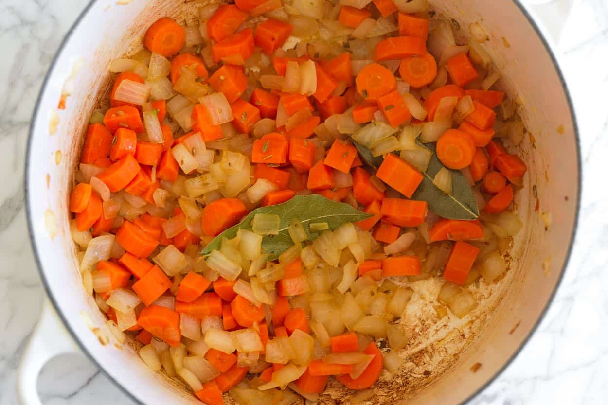 Cooking onions, carrots, garlic, fennel, and bay leaves in the soup pot
