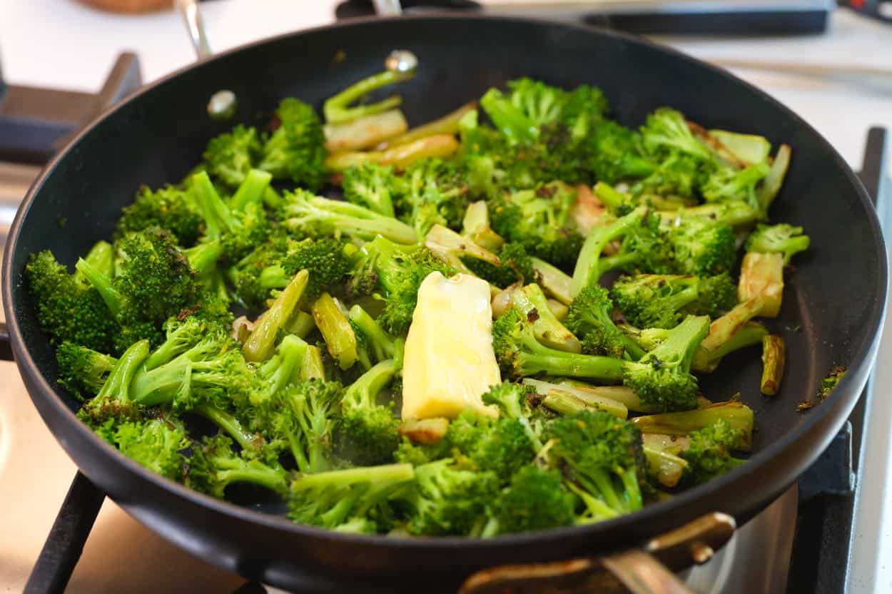 Finishing the sautéed broccoli with a little bit of butter before serving.