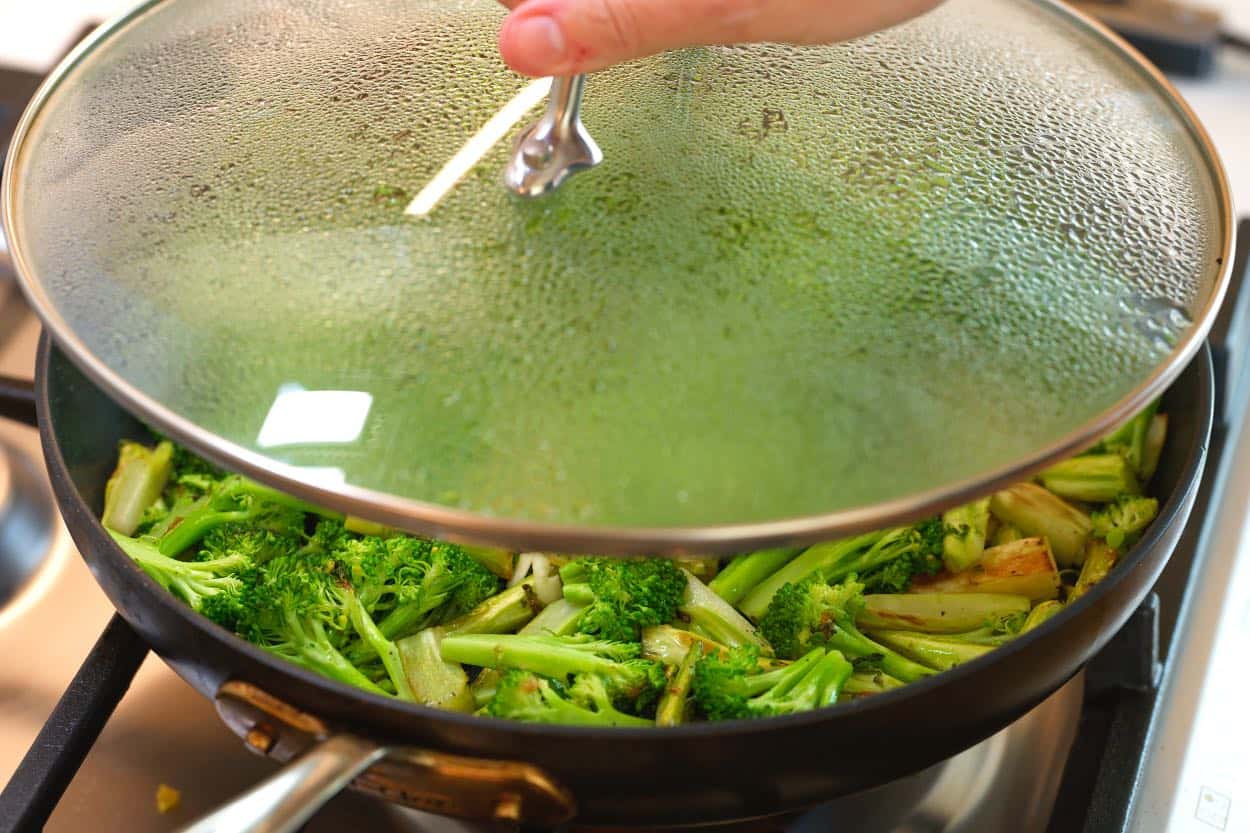 Briefly covering the broccoli in the skillet so it steams and becomes bright green and tender.