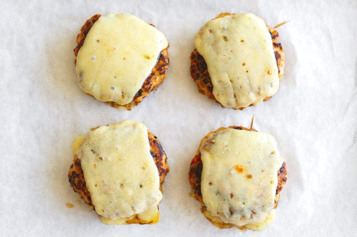 Chicken burgers ready to eat with melted cheese on top.