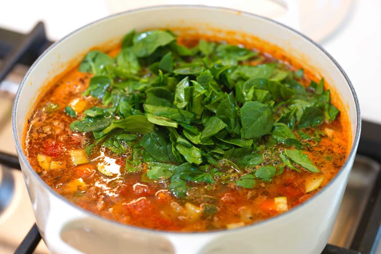 Finishing the minestrone with fresh spinach stirred into the soup at the end.