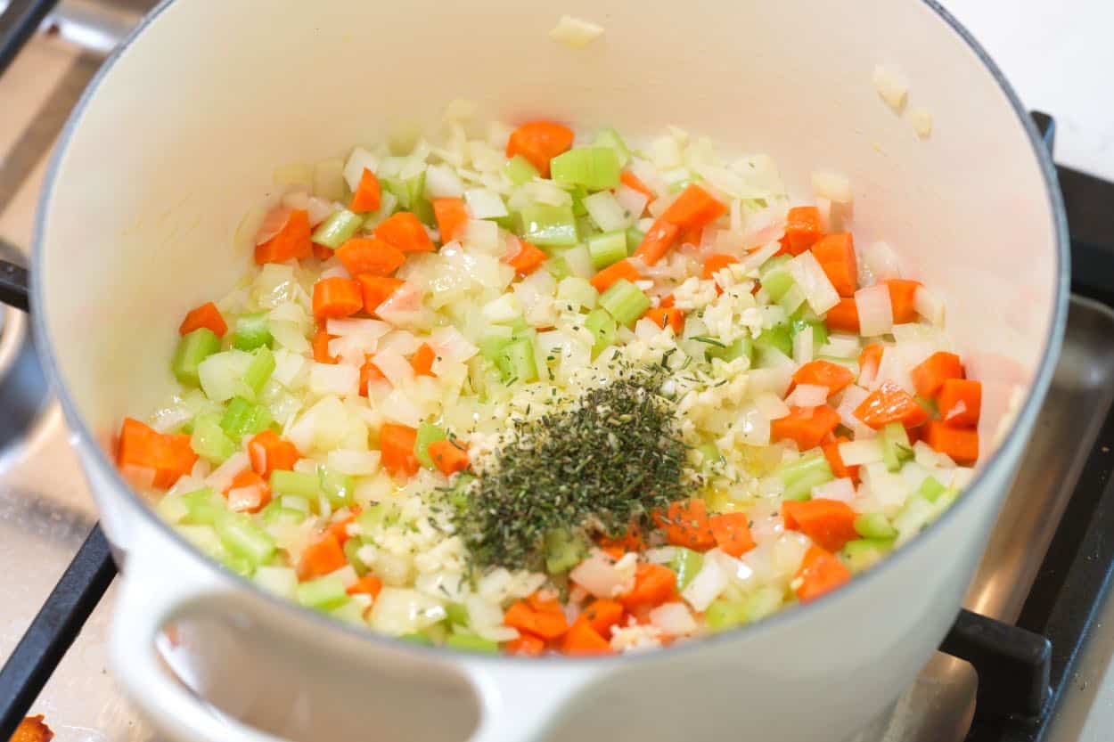 Sweating onion, carrot, and celery in olive oil in a soup pot, then adding garlic and rosemary.