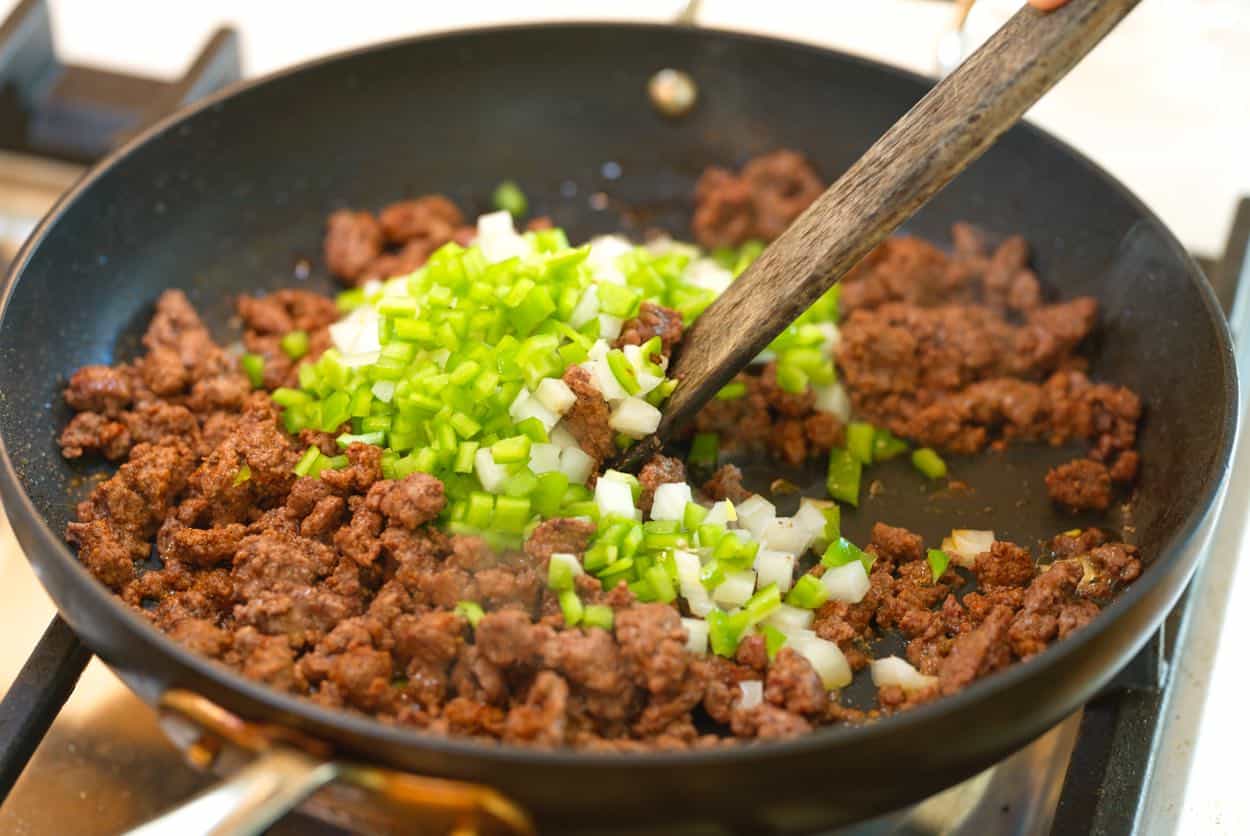 Adding onion and chopped Anaheim pepper to spice ground beef for beef tacos