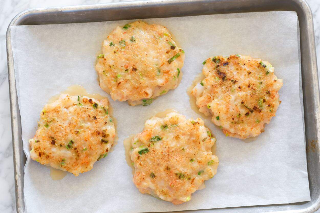 Shrimp burgers on a baking sheet ready for the oven