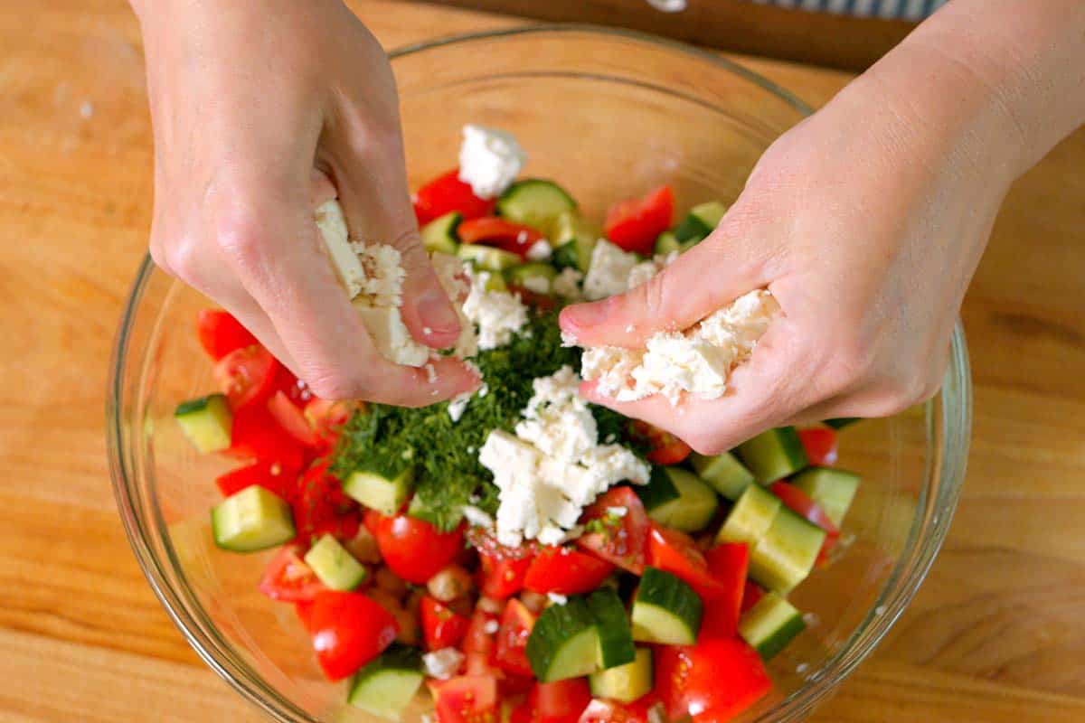 Crumbling feta cheese into the salad