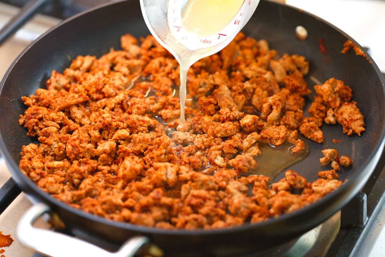 Stirring broth into ground turkey taco meat