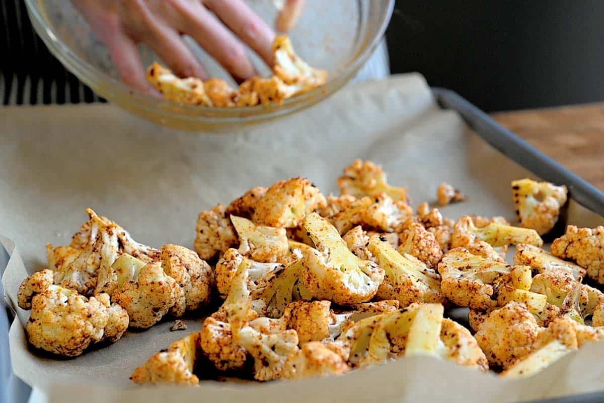 Placing cauliflower tossed with spices and oil onto a baking sheet