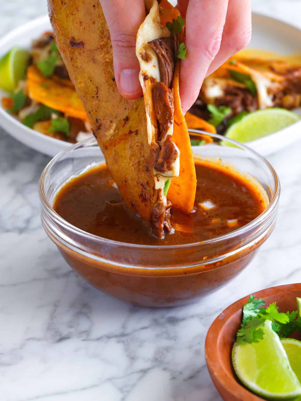 Dipping birria taco into consomé