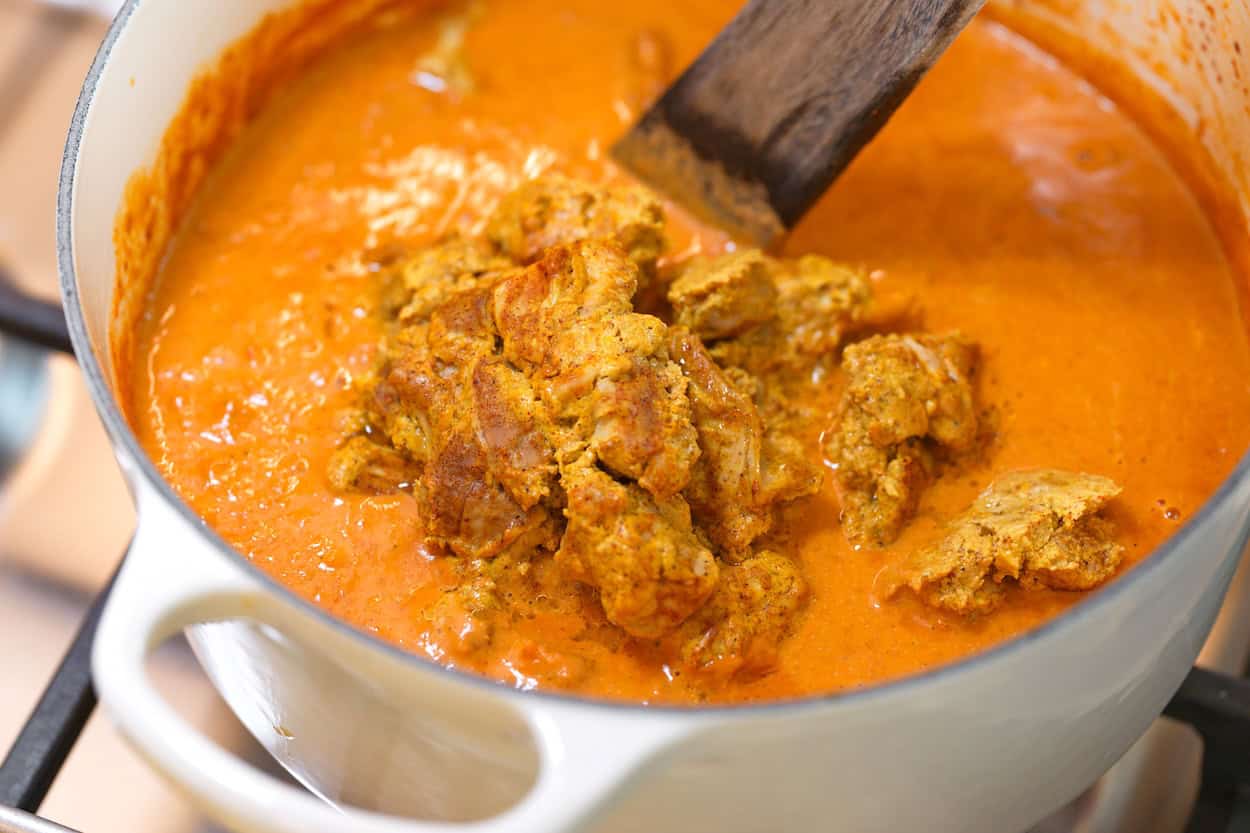 Stirring the baked chicken thighs into the tikka masala sauce